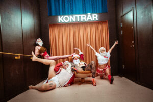 Fyra halvklädda tomtar framför en scen