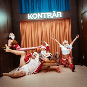 Fyra halvklädda tomtar framför en scen